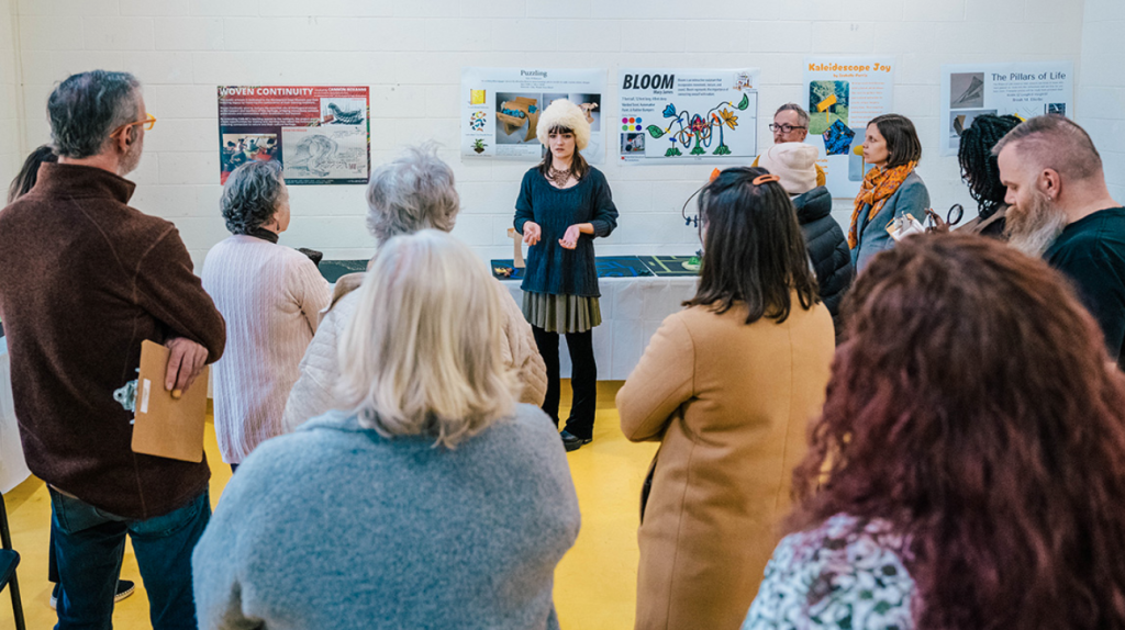 A student presents in front of their post to several older adults
